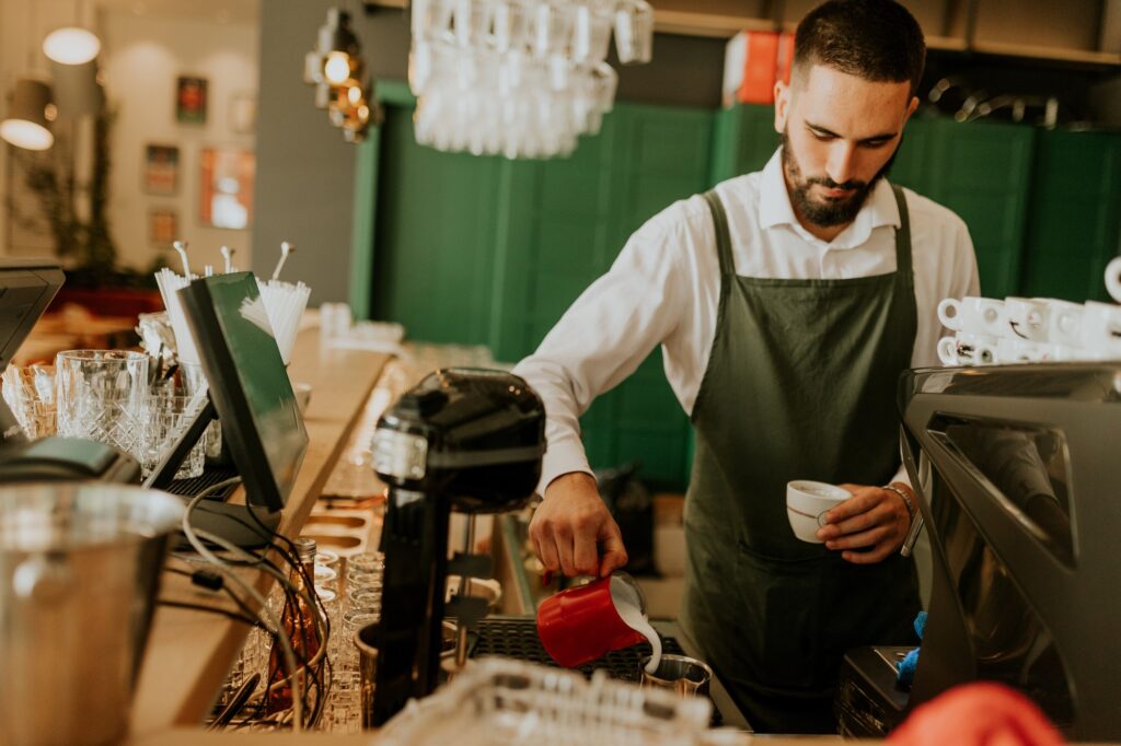 Artisan barista skillfully pours milk into a delicate cup of coffee